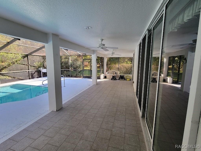 view of pool with glass enclosure, ceiling fan, and a patio area