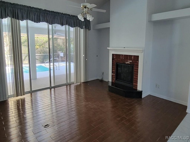 unfurnished living room featuring ceiling fan, dark hardwood / wood-style flooring, and a brick fireplace