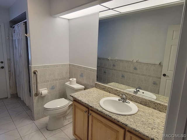 bathroom with tile patterned floors, vanity, toilet, and tile walls