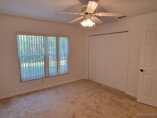 unfurnished bedroom with ceiling fan, a closet, and light colored carpet