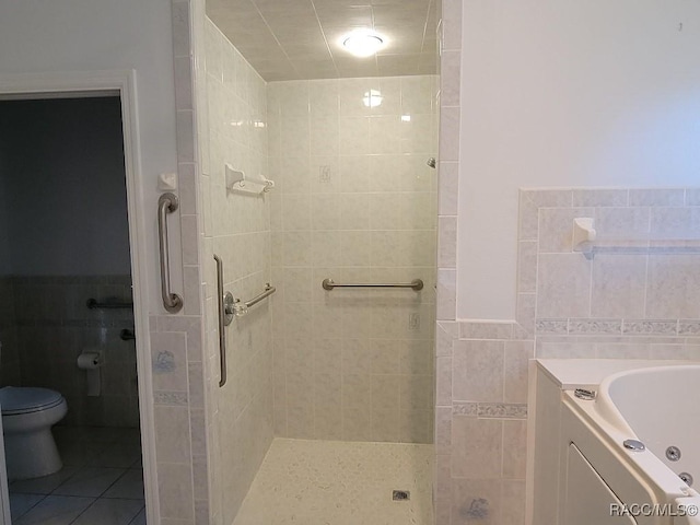 bathroom featuring tile patterned floors, toilet, tile walls, and independent shower and bath