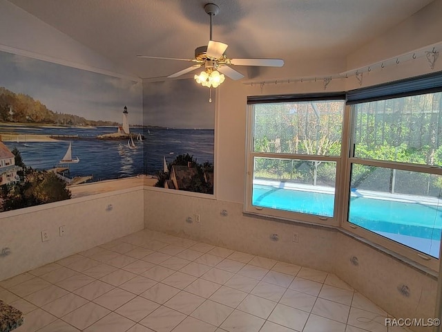 tiled spare room featuring vaulted ceiling and ceiling fan