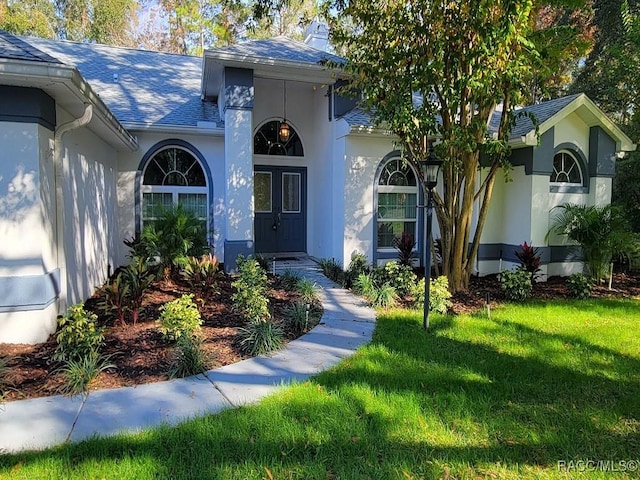 view of exterior entry featuring a lawn