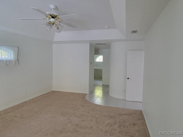 carpeted spare room featuring a raised ceiling and ceiling fan