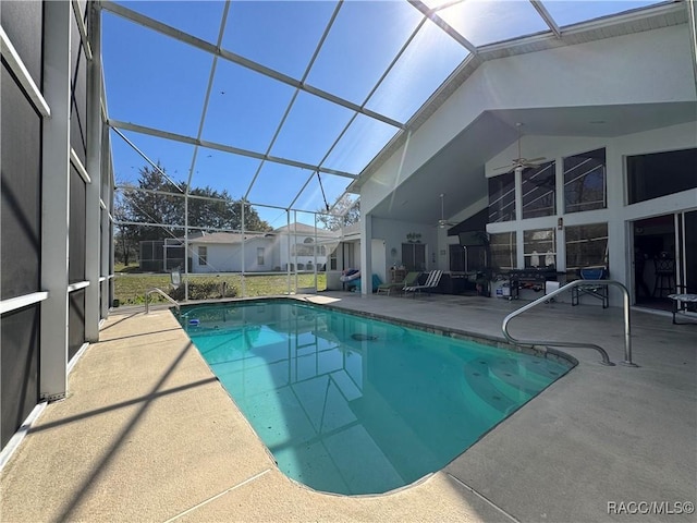 outdoor pool with glass enclosure, a patio area, and ceiling fan