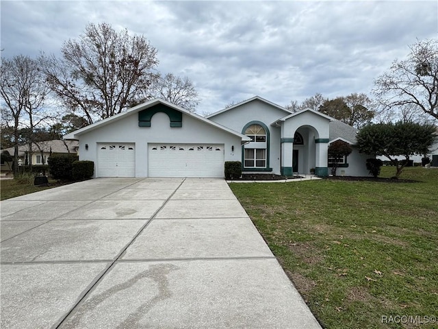 view of front of home featuring concrete driveway, an attached garage, a front lawn, and stucco siding