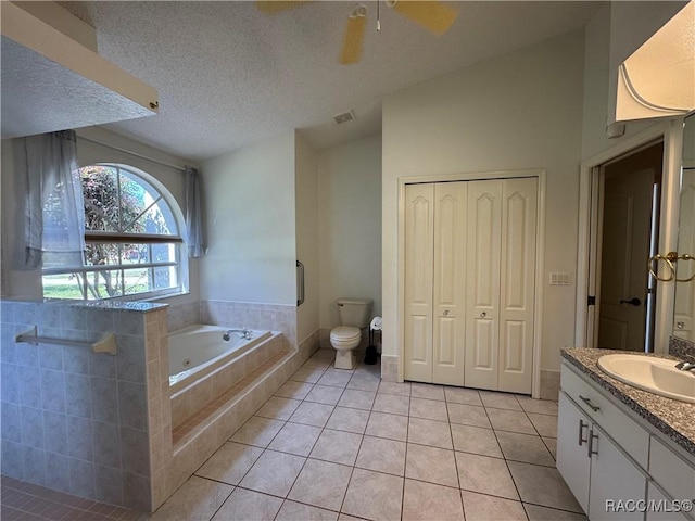 bathroom featuring vaulted ceiling, vanity, tile patterned floors, a whirlpool tub, and toilet