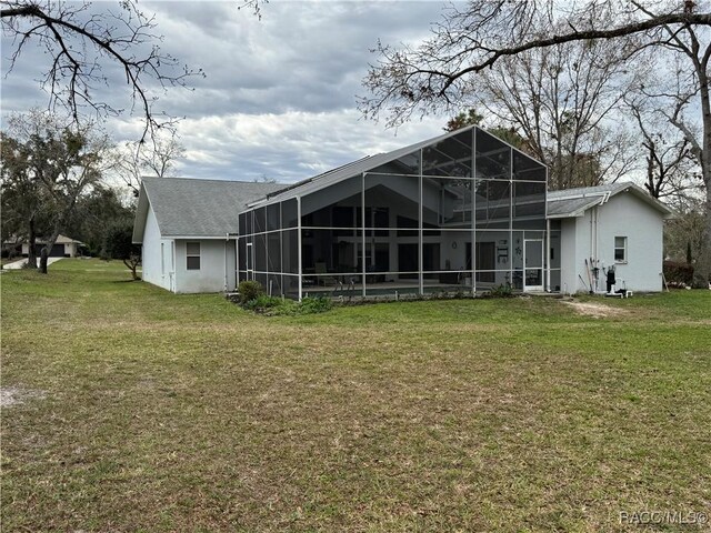 back of house featuring glass enclosure and a yard