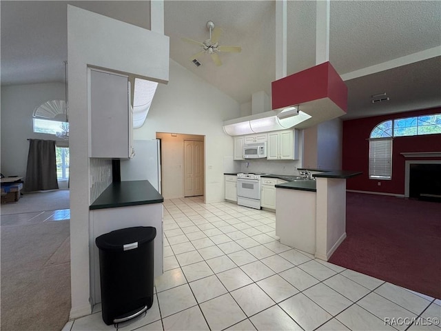 kitchen featuring dark countertops, a peninsula, white appliances, and ceiling fan