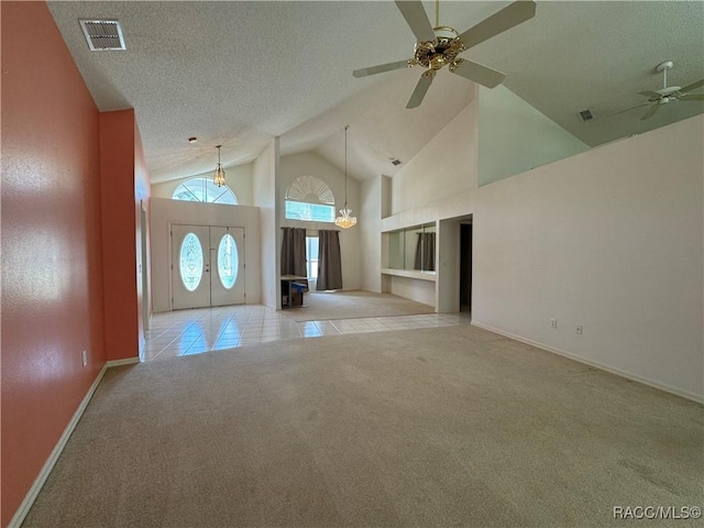 carpeted entryway with visible vents, tile patterned flooring, baseboards, high vaulted ceiling, and a ceiling fan