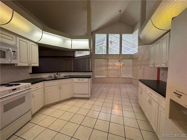 kitchen with lofted ceiling, dark countertops, white appliances, a sink, and light tile patterned floors