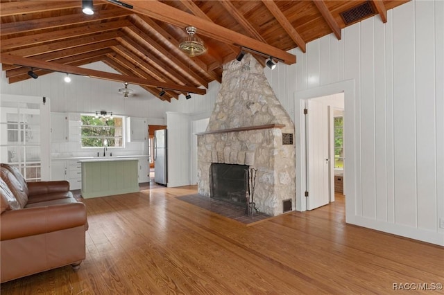 3184 N Edward Island Pt, Hernando, FL 34442 - unfurnished living room featuring light wood finished floors, a stone fireplace, high vaulted ceiling, wood ceiling with exposed beams, and wood walls