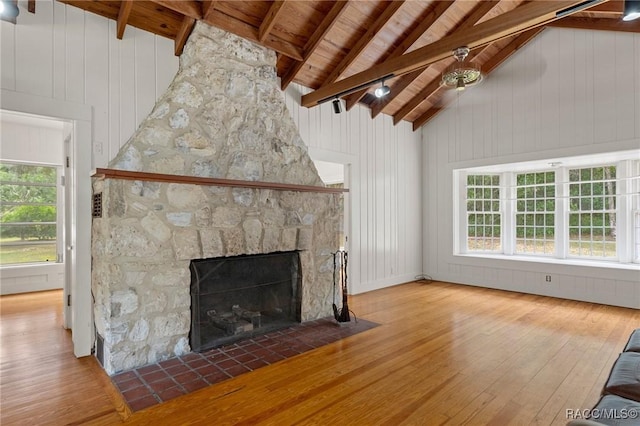 3184 N Edward Island Pt, Hernando, FL 34442 - unfurnished living room featuring wood-type flooring, high vaulted ceiling, wood ceiling with exposed beams, a stone fireplace, and wooden walls