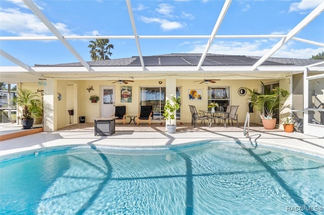 view of swimming pool featuring a patio, glass enclosure, and ceiling fan