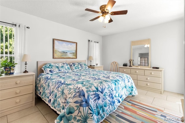 bedroom with ceiling fan, light tile patterned floors, and a textured ceiling