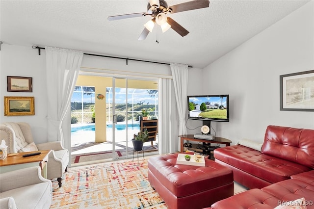 living room with a textured ceiling, ceiling fan, and vaulted ceiling