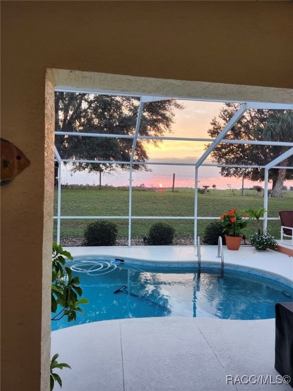 pool at dusk with a lanai and a patio