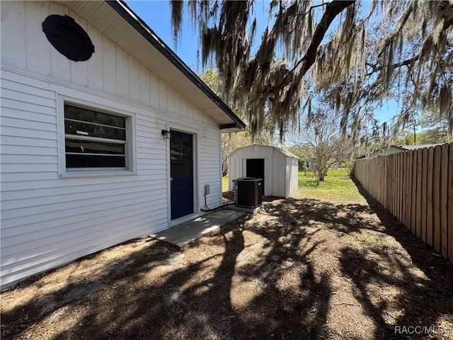 view of yard with central air condition unit, a storage shed, an outdoor structure, and fence