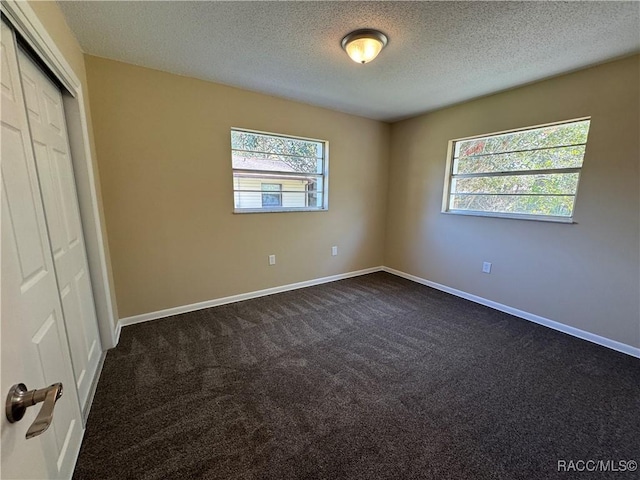 unfurnished bedroom with a closet, dark carpet, and baseboards