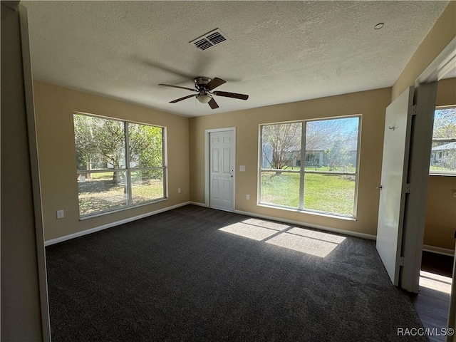 spare room featuring visible vents, baseboards, ceiling fan, and dark colored carpet