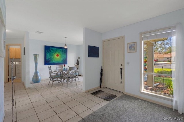 foyer entrance featuring light tile patterned floors, washing machine and dryer, visible vents, and baseboards