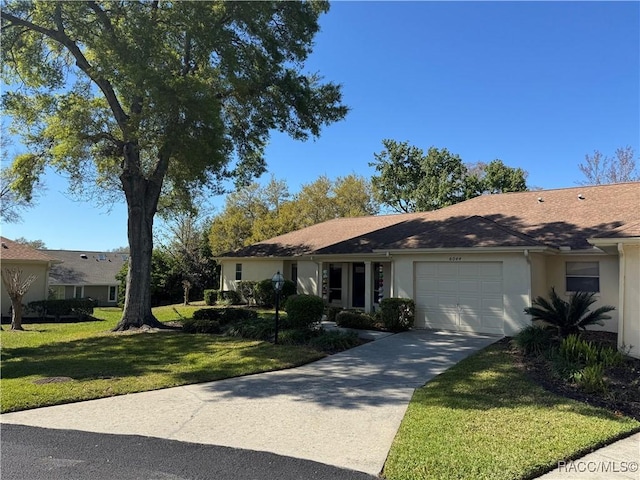 ranch-style house with a front lawn, an attached garage, driveway, and stucco siding