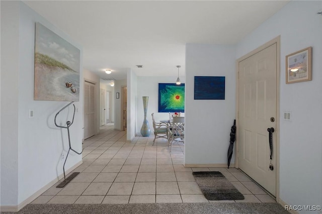 corridor featuring light tile patterned floors, visible vents, and baseboards