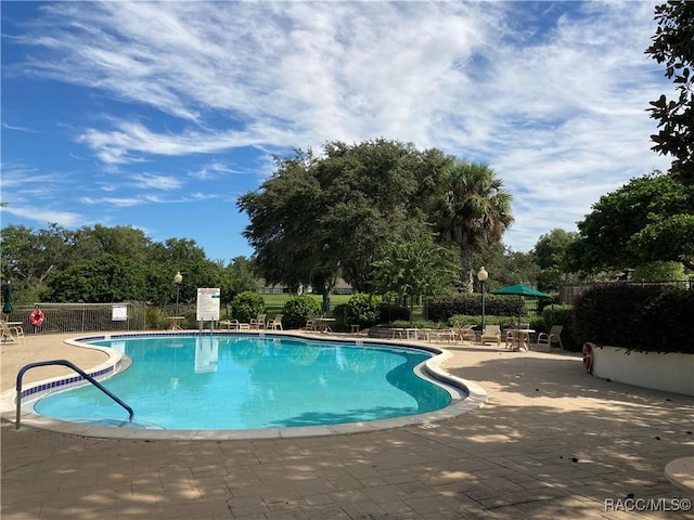 pool with a patio and fence