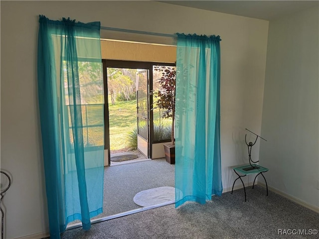 doorway to outside with baseboards and carpet flooring