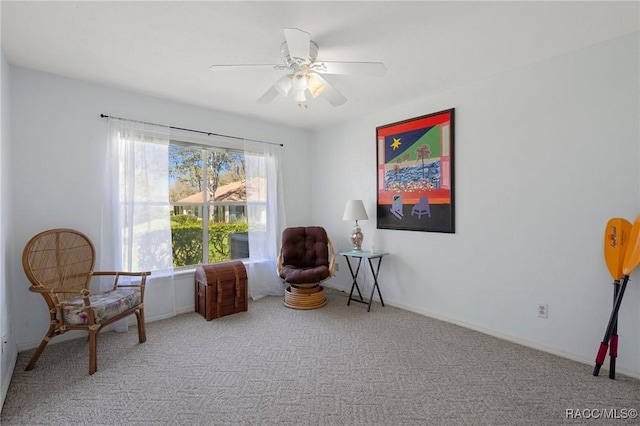 living area featuring carpet flooring, baseboards, and a ceiling fan