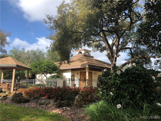 view of side of home featuring a gazebo, stucco siding, and fence