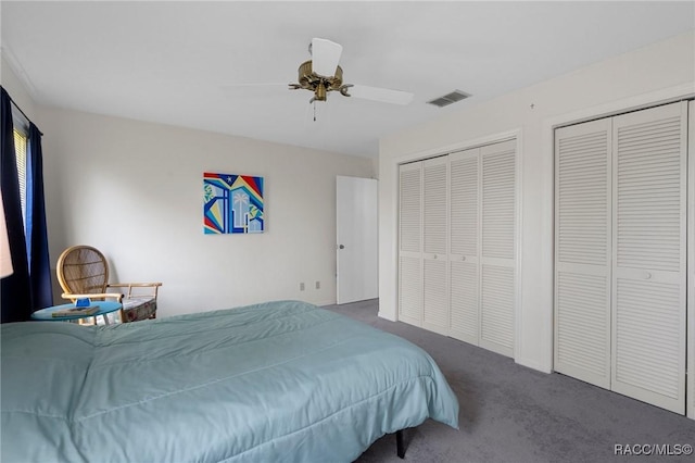 carpeted bedroom featuring a ceiling fan, visible vents, and multiple closets