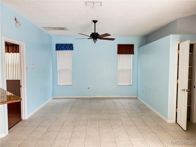 tiled spare room with a textured ceiling and ceiling fan