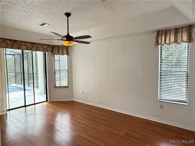 unfurnished room with hardwood / wood-style flooring, plenty of natural light, and a textured ceiling