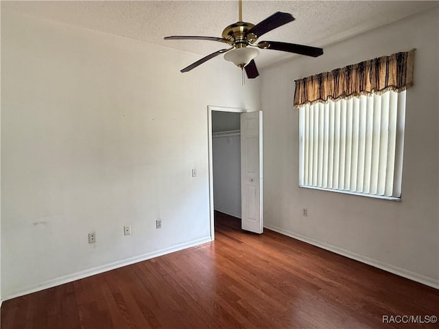 unfurnished bedroom featuring ceiling fan, a closet, dark hardwood / wood-style flooring, and a textured ceiling