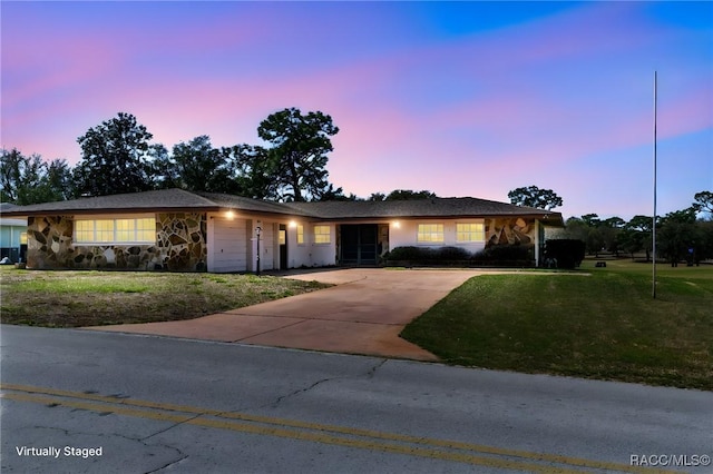 ranch-style house with a garage, a front yard, stone siding, and driveway