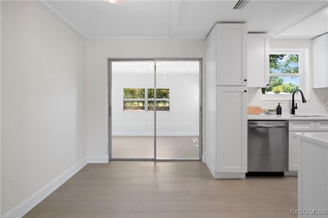 kitchen with stainless steel dishwasher, baseboards, light countertops, white cabinets, and a sink