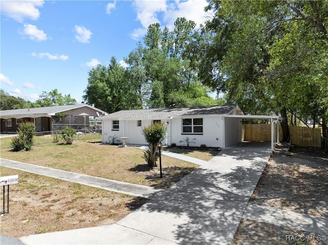 view of front of home with fence, an attached carport, driveway, and a front lawn