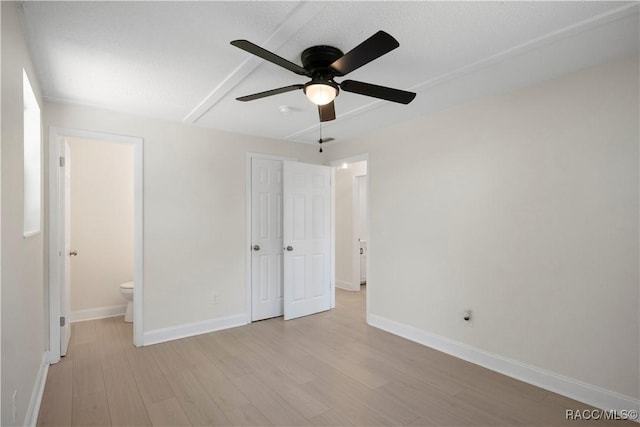 unfurnished bedroom with baseboards, ceiling fan, light wood-type flooring, and connected bathroom
