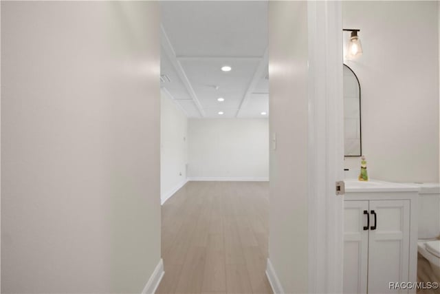 hall featuring recessed lighting, baseboards, a sink, and light wood-style flooring