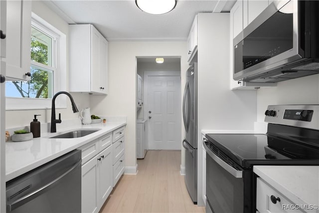 kitchen featuring stainless steel appliances, white cabinetry, and a sink