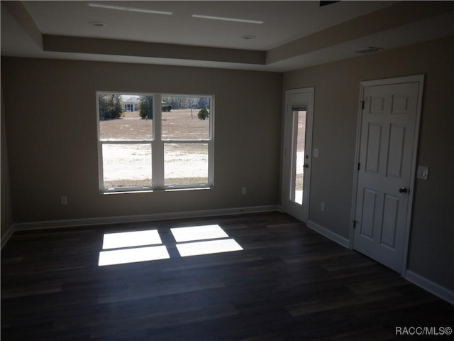 unfurnished room featuring dark hardwood / wood-style flooring and a raised ceiling