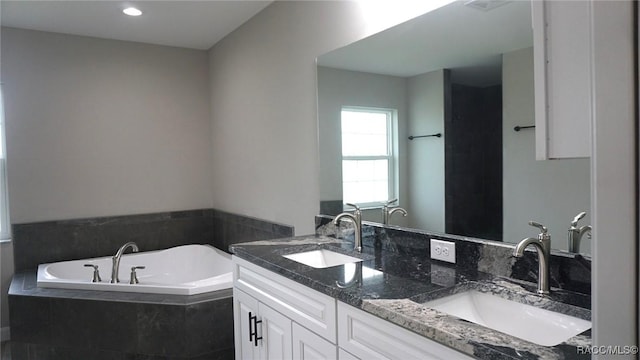 bathroom with vanity and tiled bath