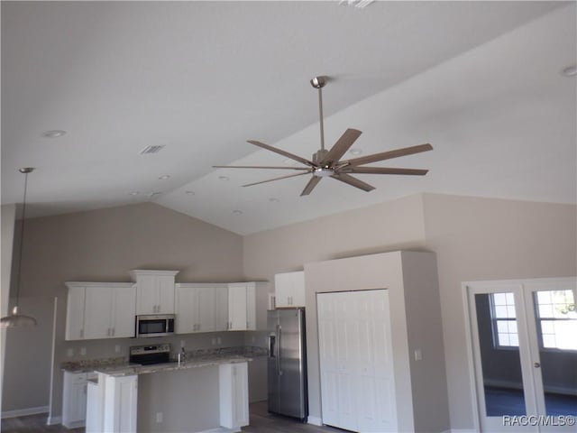 kitchen featuring white cabinetry, light stone counters, decorative light fixtures, appliances with stainless steel finishes, and a kitchen island with sink