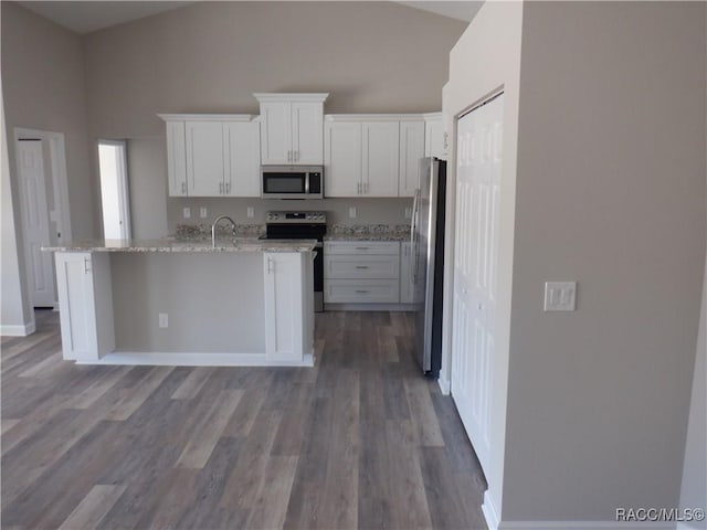 kitchen featuring white cabinetry, high vaulted ceiling, a center island with sink, stainless steel appliances, and light stone countertops