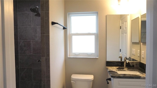 bathroom featuring tiled shower, vanity, and toilet