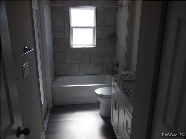 full bathroom featuring vanity, tiled shower / bath, hardwood / wood-style flooring, and toilet