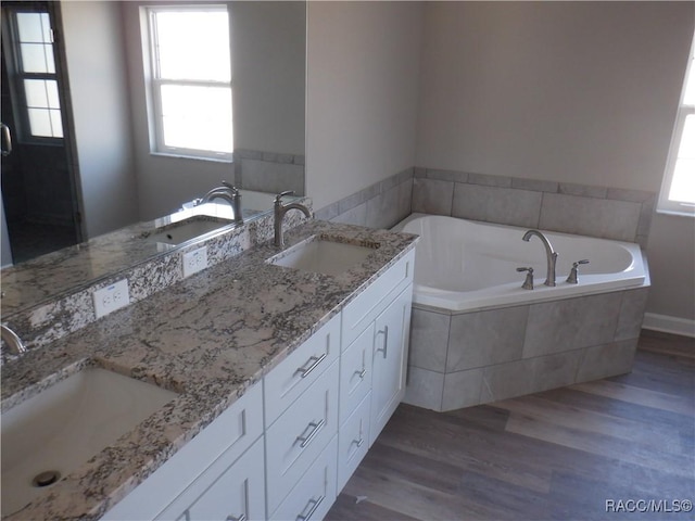 bathroom with vanity, hardwood / wood-style floors, and a relaxing tiled tub