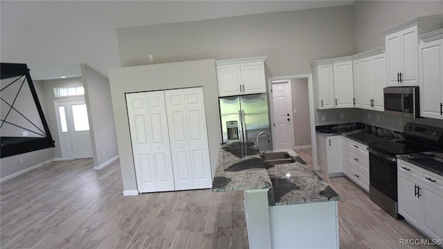 kitchen with white cabinetry, sink, a towering ceiling, and stainless steel appliances