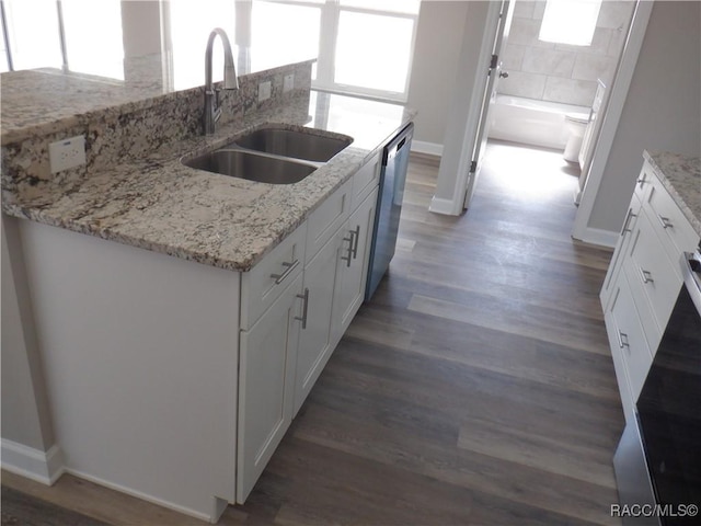 kitchen with white cabinetry, dishwasher, sink, and a center island with sink